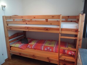 A bunk bed with a wooden frame and a colorful bedspread.