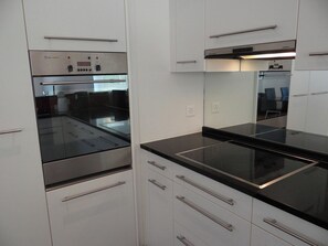A modern kitchen with stainless steel appliances, white cabinetry, and a black countertop.