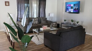Una sala de estar moderna con un sofá, una mesa de centro y un televisor de pantalla plana montado en la pared.