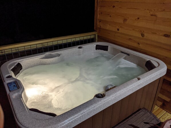 A hot tub with a control panel and a wooden wall in the background. - Faye's Retreat (Fort Payne)