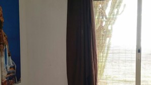 Een hotelkamer met een bed, een stoel bij een raam met uitzicht, een lamp op een nachtkastje en een schilderij aan de muur.