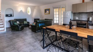 Un vaste espace de vie comprenant une table à manger en bois, des chaises noires et un canapé en cuir vert.