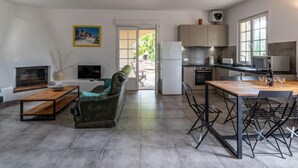 Un salon moderne comprenant un canapé, un téléviseur et un coin repas avec des chaises et une table.