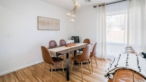 Et moderne spiseområde med et træbord, brune stole og en lysekrone.