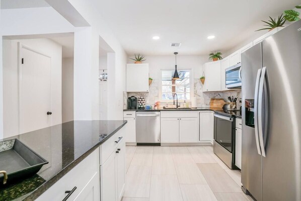 A modern kitchen with white cabinets, stainless steel appliances, and a black countertop. - This house is a 4 bedroom(s), 1.5 bathrooms, located in Wichita, KS. (Wichita)
