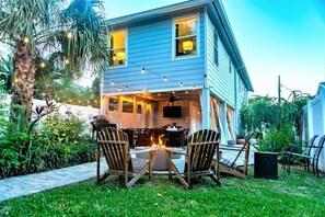 Une maison avec un patio, un espace salon extérieur et un foyer.