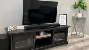 A black entertainment center with a flat-screen TV, a small plant, and a framed sign. - Central Frisco-Full renovated cozy&nice half duplex 3bed|2bath free wifi&parking (Frisco)