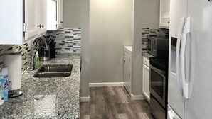 A kitchen with white cabinets, a granite countertop, a stainless steel sink, a microwave, an oven, and a refrigerator. - Central Frisco-Full renovated cozy&nice half duplex 3bed|2bath free wifi&parking (Frisco)