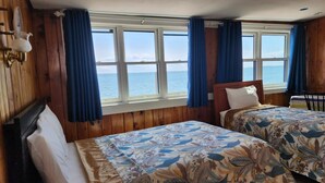 A room with two beds, wooden walls, a view of the sea, and a window with curtains. - Unwind at the Scallop Saturday cottage located at the Oceana Cottages (North Truro)
