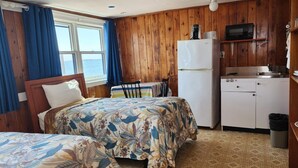 A room with two beds, a small kitchenette, and a view of the sea. - Unwind at the Scallop Saturday cottage located at the Oceana Cottages (North Truro)