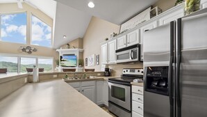 Una cocina moderna con una isla grande, electrodomésticos de acero inoxidable y vistas al exterior.