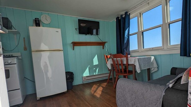 A compact room with a kitchenette, a dining area, and a sleeping area.