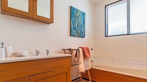 A bathroom with wooden cabinets, a sink, a towel rack, and a window with blinds.