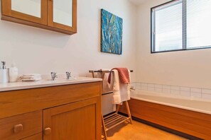A bathroom with wooden cabinets, a sink, a towel rack, and a window with blinds.