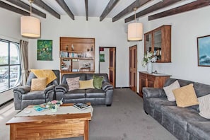 Ein geräumiges Wohnzimmer mit zwei Ledersofas, einem Holztisch und einem Bücherregal.