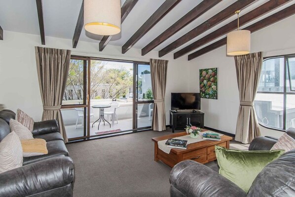 A modern living room with a leather sofa, a coffee table, and a TV.