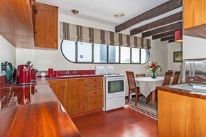 Eine kompakte Küche mit Holzausbau, einem Herd und einer Essecke mit Tisch und Stühlen.