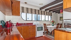 Une cuisine compacte avec des meubles de rangement en bois, une cuisinière et un coin repas comprenant une table et des chaises.