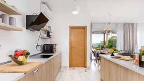 Una cocina moderna con armarios de madera, microondas integrado y un amplio ventanal con vistas al exterior.