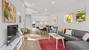 A modern living room with a grey sofa, a red rug, and a flat-screen TV. - Villa 17  Beaches Bush Wineries and more (Dunsborough)