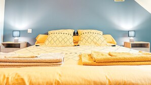 Een slaapkamer met een bed, twee nachtkastjes, twee lampen, twee kussens, twee dekens, twee handdoeken en twee ingelijste foto's aan de muur.