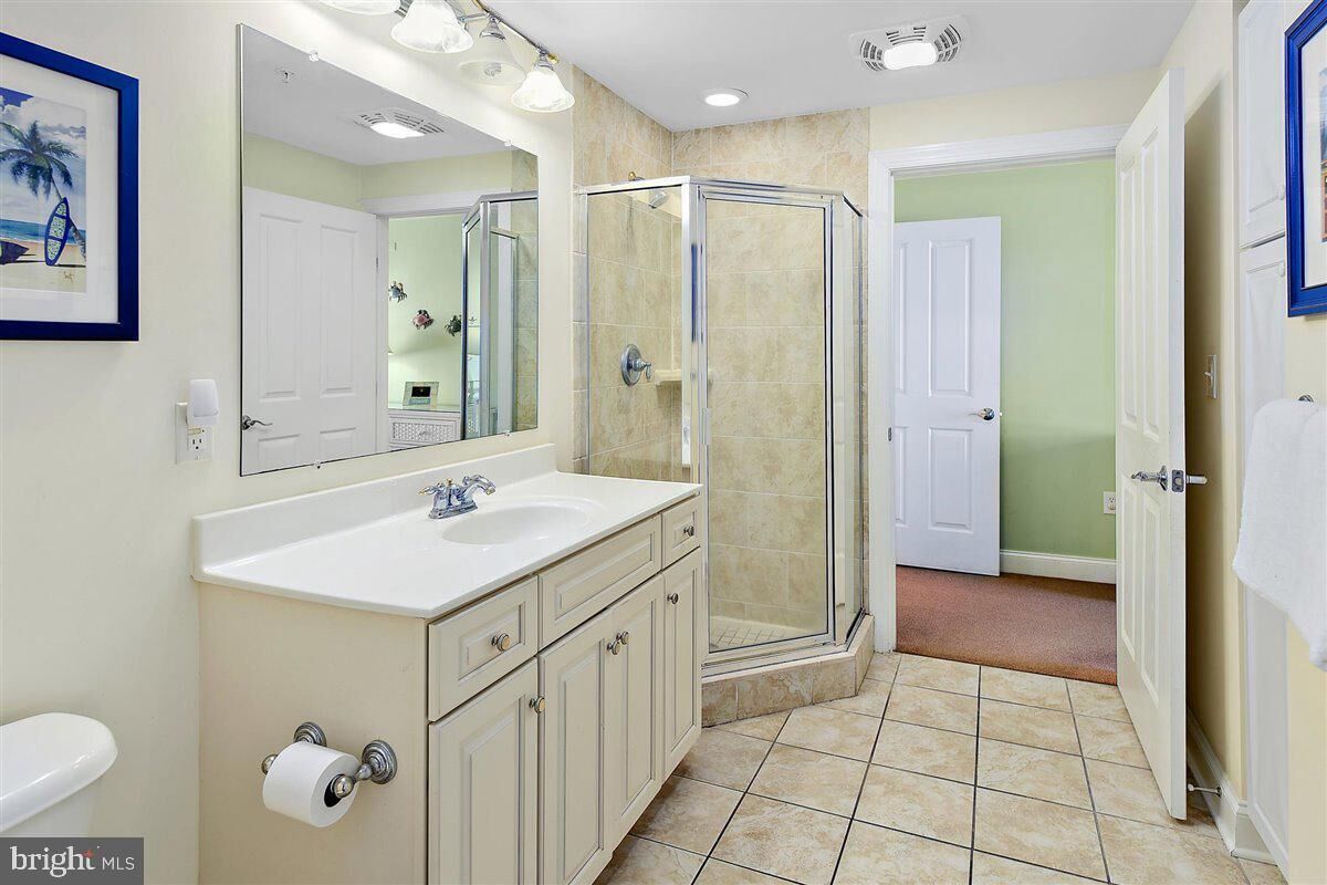 A bathroom with a white sink, a large mirror, a glass shower enclosure, and a toilet.