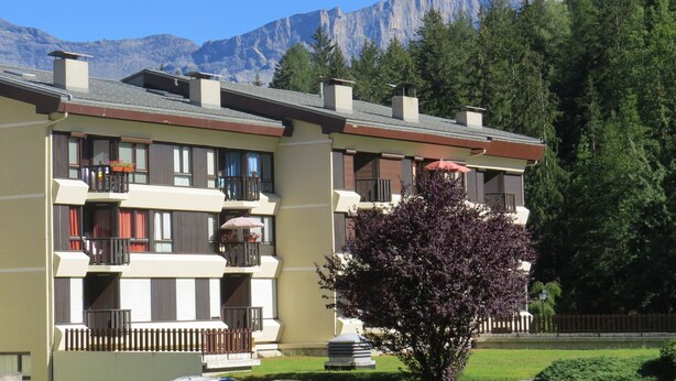 Un hôtel à plusieurs étages doté de balcons, d’un jardin et offrant une vue sur les montagnes.