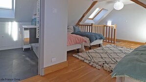 Ein Schlafzimmer mit schrägem Dach, einem Bett, einem Schreibtisch und einem Fenster.