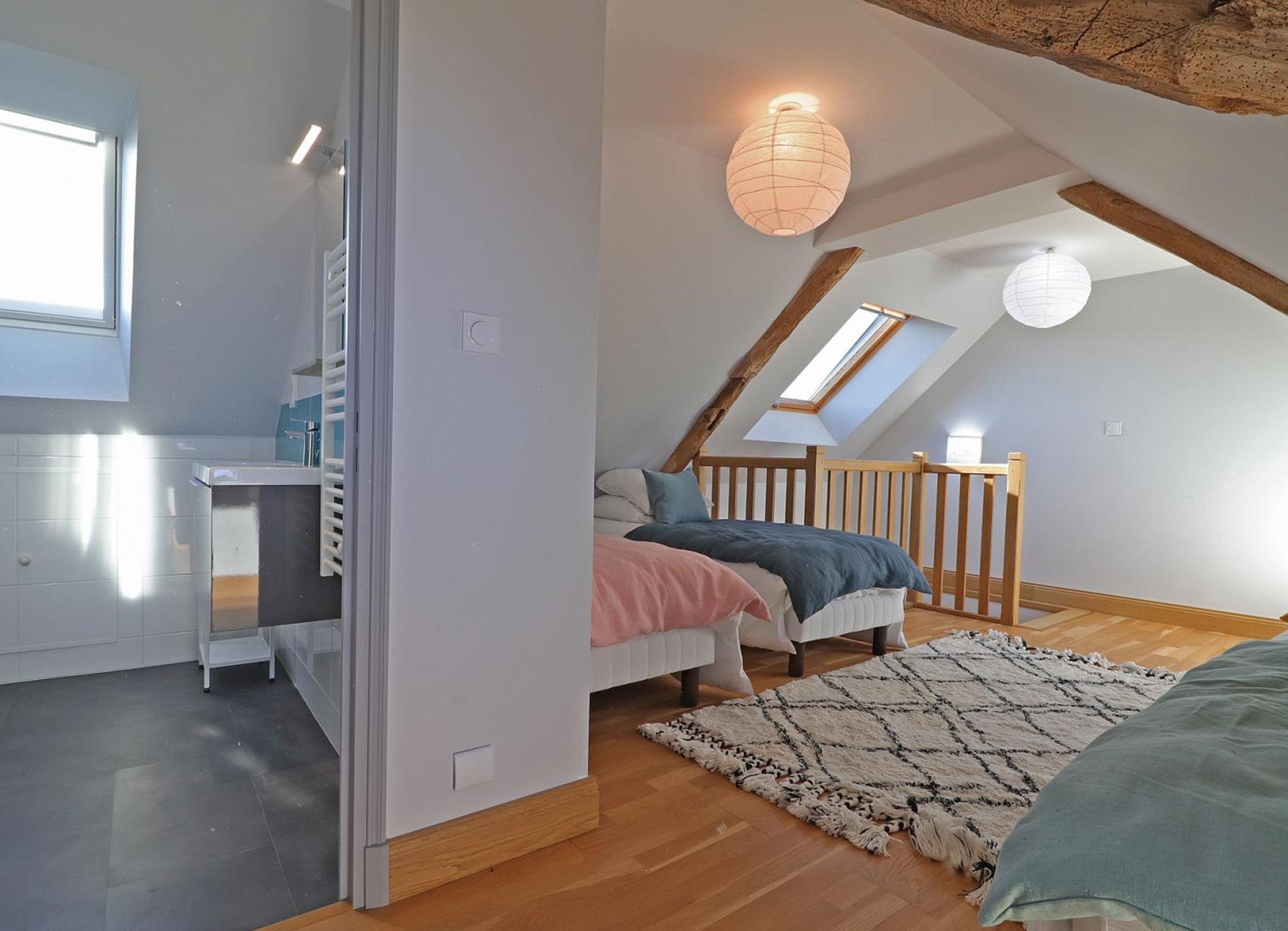 Een slaapkamer met een schuine kap, een bed, een bureau en een raam.