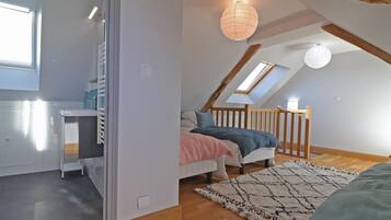 Een slaapkamer met een schuine kap, een bed, een bureau en een raam.