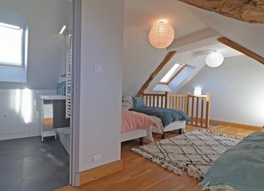 Ein Schlafzimmer mit schrägem Dach, einem Bett, einem Schreibtisch und einem Fenster.