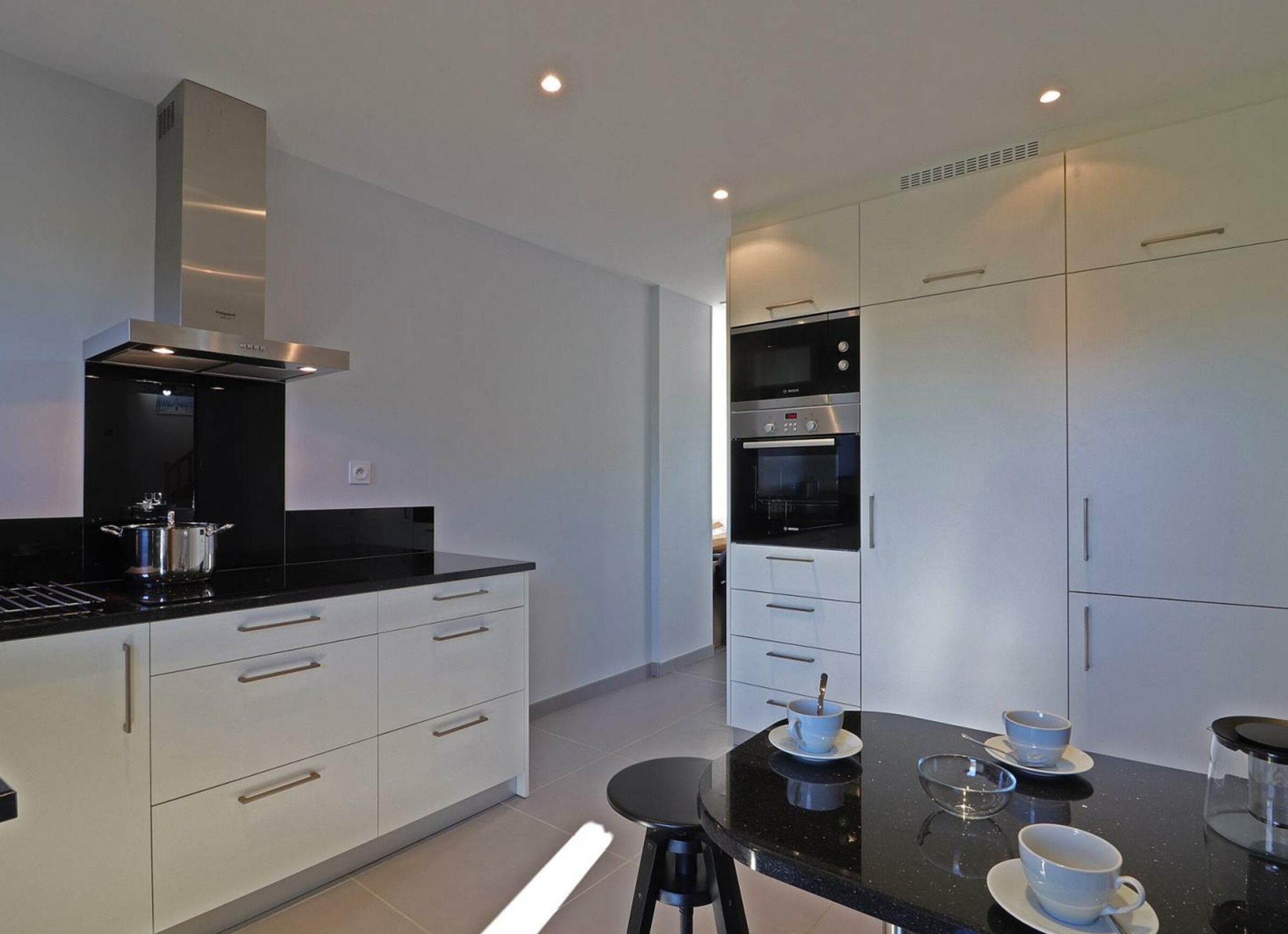 A modern kitchen with white cabinetry, a black countertop, and stainless steel appliances.
