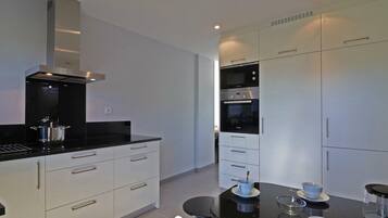 A modern kitchen with white cabinetry, a black countertop, and stainless steel appliances.