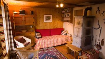 A cozy room with a wooden interior, a red sofa, a fireplace, and a dining table.