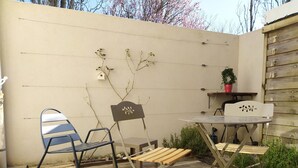 Een houten terras met een metalen tafel en twee stoelen.
