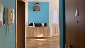 Cocina moderna con pared azul, armarios de madera, microondas, tostadora, hervidor y teléfono.