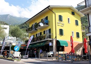 Un edificio amarillo con balcones, una cafetería y un letrero de alquiler de bicicletas.