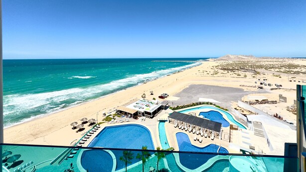 Un resort con un amplio espacio de piscina, playa y vistas al océano.