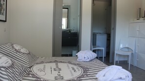 Hotellihuone, jossa on sänky, tuoli, työpöytä ja vaatekaappi.