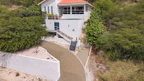 A two-story house with a red-tiled roof, a balcony, and a swimming pool.