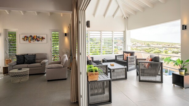 A spacious living area with a high ceiling, large windows, and a view of the cityscape.