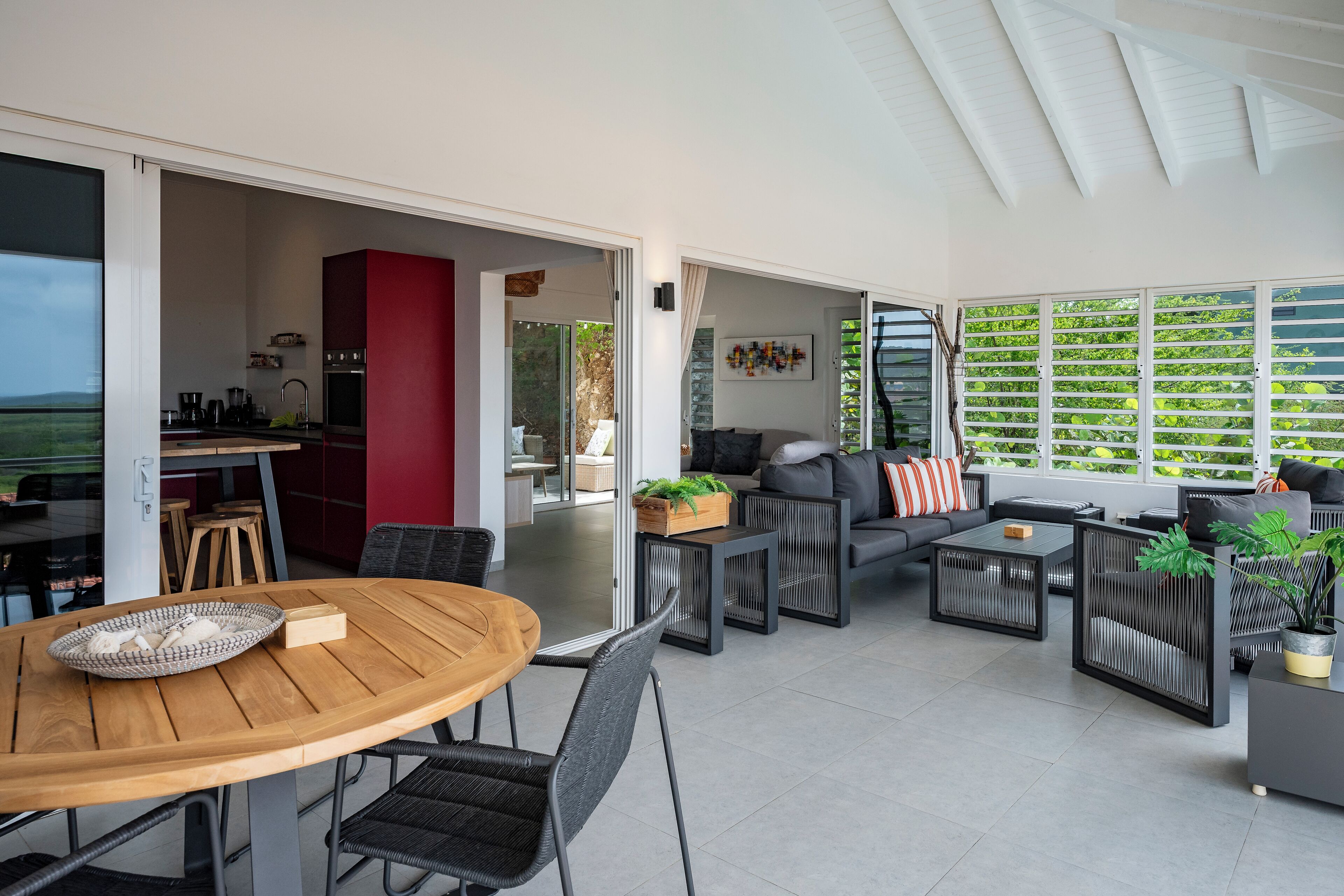An open-plan living area with a dining table, sofas, and a kitchen in the background.
