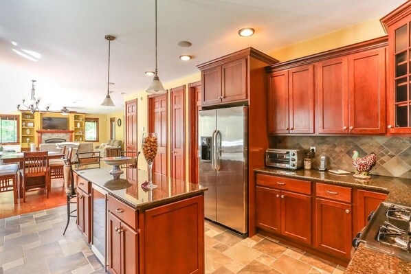 A kitchen with wooden cabinets, a stainless steel refrigerator, and a granite countertop.