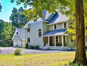 A two-story house with a porch, garage, and a well-maintained lawn. - Catskills retreat: Hot tub, ATV, hiking & fishing (Cairo)
