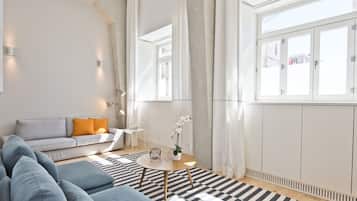 Ett modernt vardagsrum med en soffa, ett soffbord och en orkidé i en kruka.