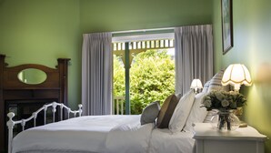 A neatly made bed with white linens and pillows, a wooden headboard, and a nightstand with a lamp and flowers. - Hillside - in central Daylesford, period home close to lake, shops and day spas (Daylesford)