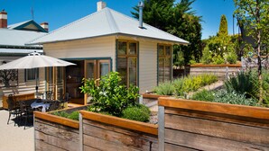 A house with a patio area featuring wooden planters and a table with chairs. - Hillside - in central Daylesford, period home close to lake, shops and day spas (Daylesford)