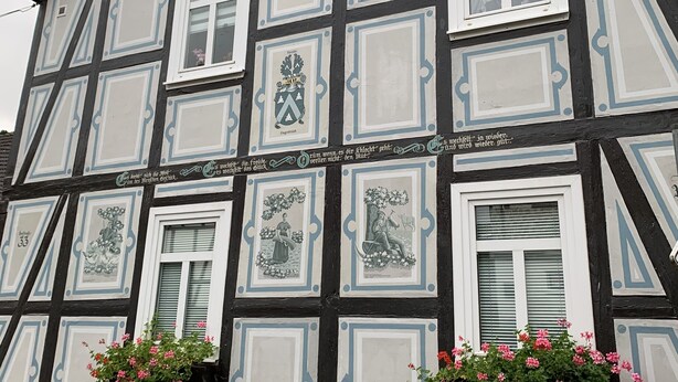 A traditional half-timbered building with multiple windows and decorative panels.