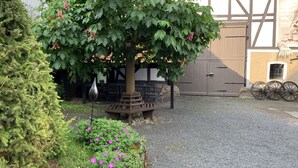 A garden area with a bench, a tree with pink flowers, and a building with a large garage door.