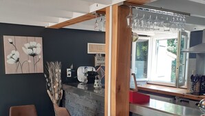 A modern kitchen with a stone backsplash, wooden beams, and a bar area with stools.